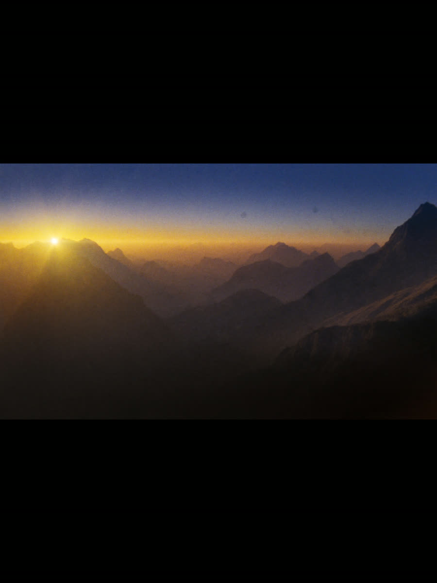 First light of dawn breaking over a horizon of distant mountain peaks